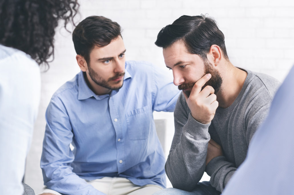 Understanding people giving support to depressed man at group therapy session