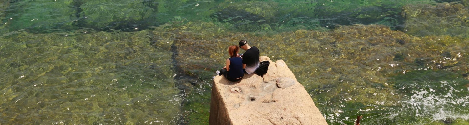 s couple sitting on a stone pier on a sea shore