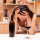 a woman drinking red wine and holding her head