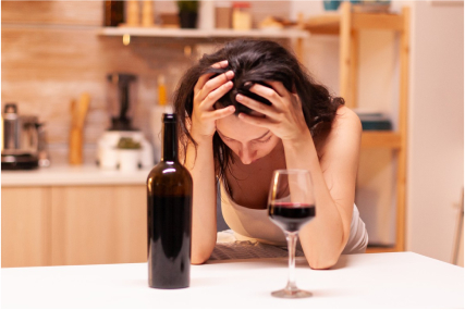 a woman drinking red wine and holding her head