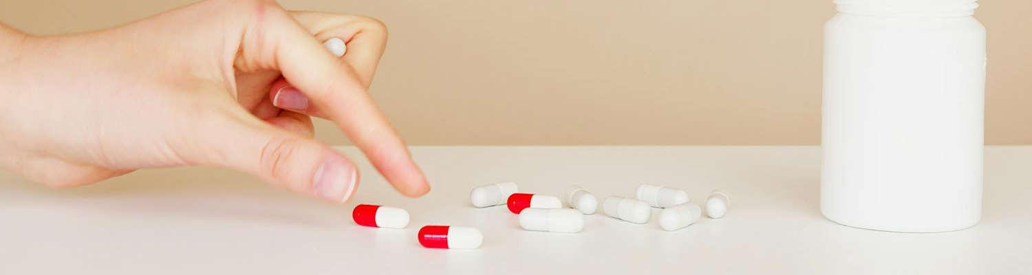 A peroson picking up pills from a table. 