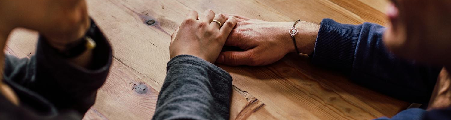 Two people holding hands in support during opiate detox program. 