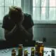 a person sits alone, surrounded by pill bottles, struggling with opiate detox