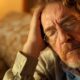 man sitting, holding his head in discomfort, experiencing potential detox side effects