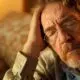 man sitting, holding his head in discomfort, experiencing potential detox side effects