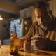 man reading prescription label, concerned about opioid use, seated at kitchen table